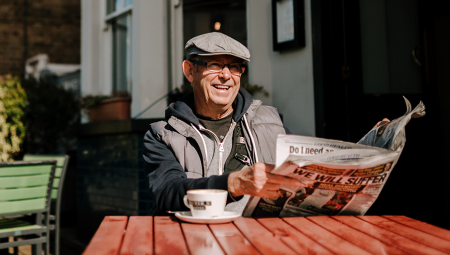 Older man reading a paper with his morning coffee