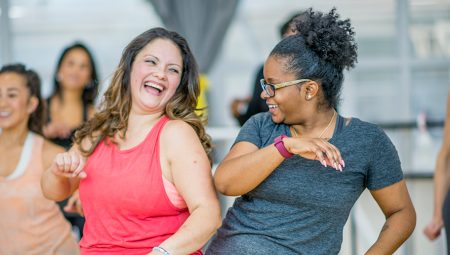 Two middle aged women enjoy an exercise class