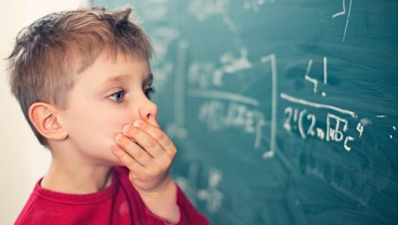Cognition: Little boy looks confused at equation on a blackboard