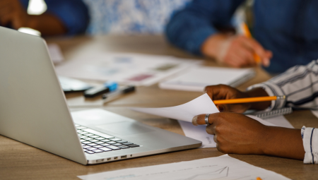 Close up on writing a note on a desk with a laptop