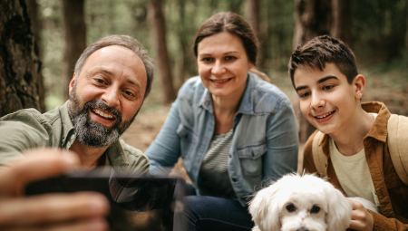 Parents take a selfie with their teenage son and family dog.