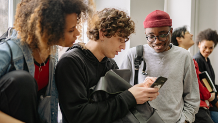 A young man shows his friends something on his phone.