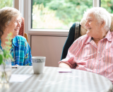 Elderly man and woman sitting down and smiling with each other