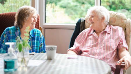 Elderly man and woman sitting down and smiling with each other