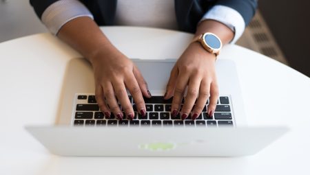 A person's hands rest on a laptop keyboard