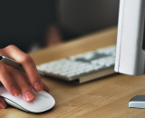 A person using a mouse and computer