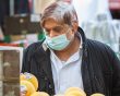Man eearing a mask shopping for fruit