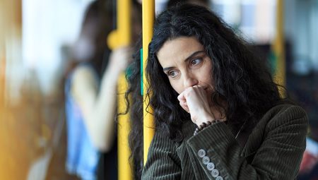 Thoughtful looking woman leans against a pole on public transport