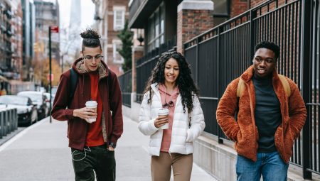 Three young adults walk down the street chatting