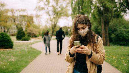 Woman wearing a mask in the park using her phone