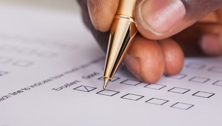 A hand holding a pen about to complete a survey question