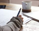 Person completing paper form with pen